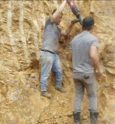 Two men climbing the sandy cliff face